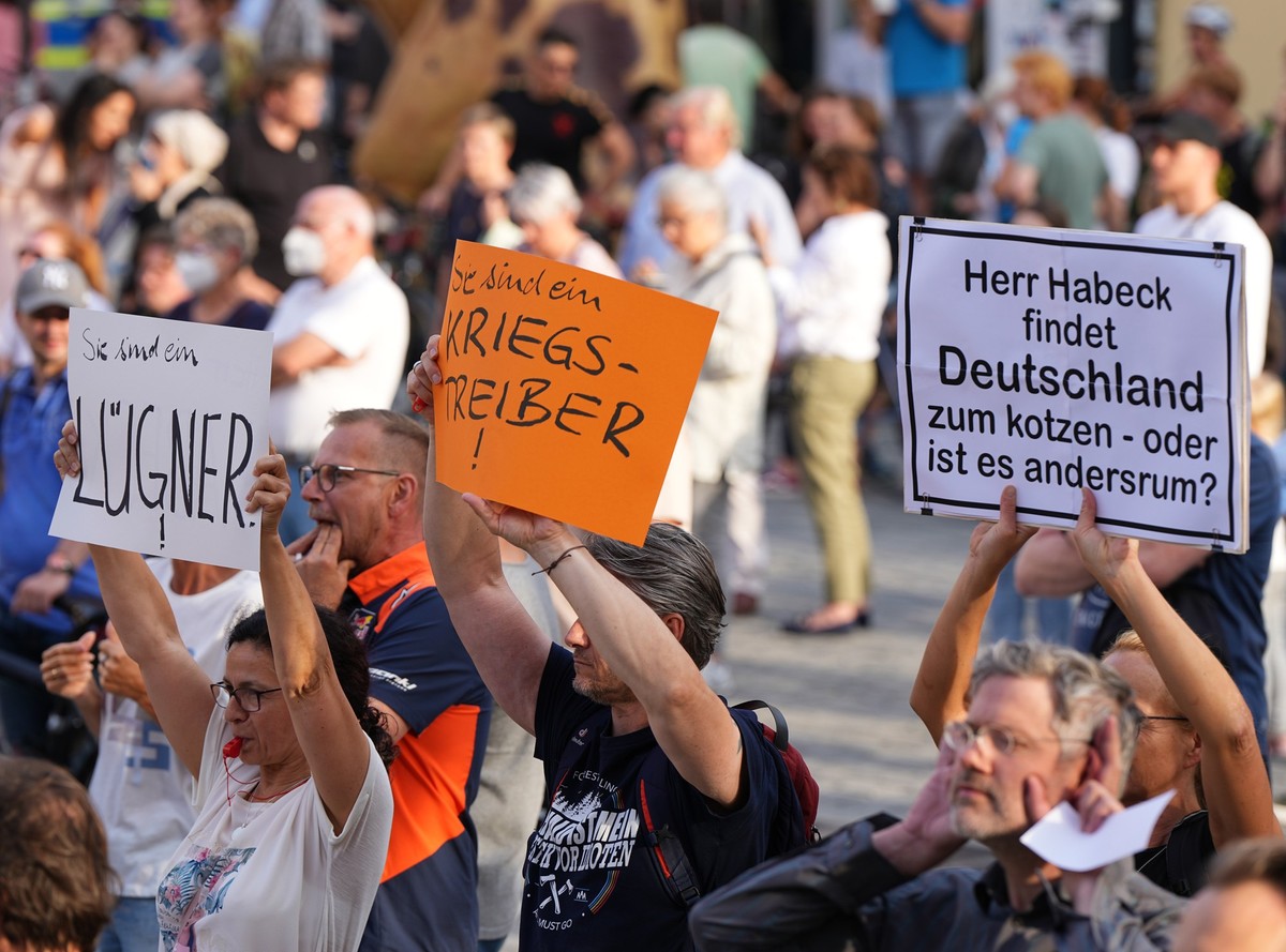 28.07.2022, Bayern, Bayreuth: Demonstranten halten w�hrend des B�rgerdialogs von Bundeswirtschaftsminister Habeck im Ehrenhof der Stadt hinter einer Absperrung Plakate mit der Aufschrift �L�gner�, �Si ...