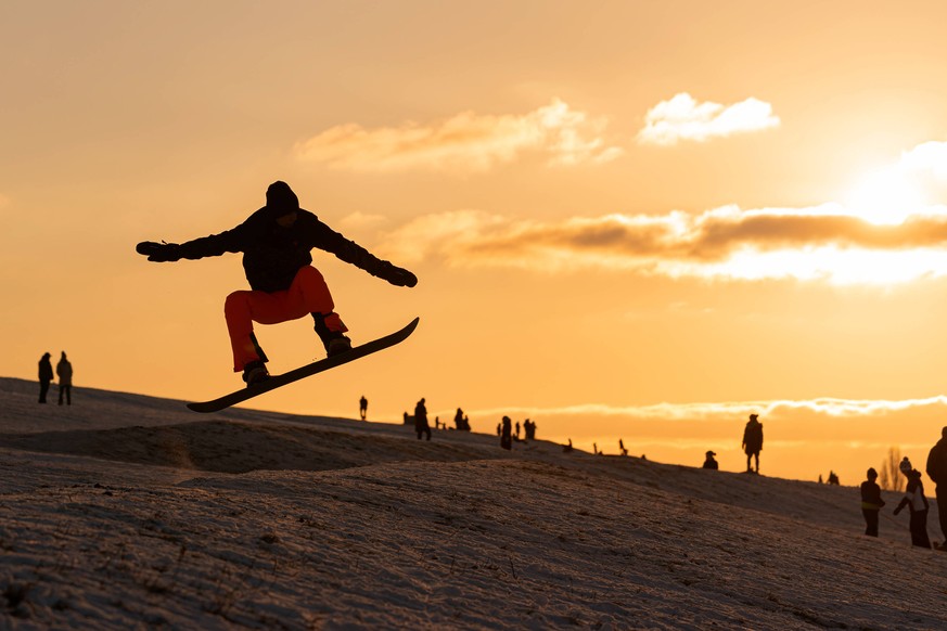 13.02.2021, Berlin, Deutschland , GER - Wintervergnügen an der der südlichen Stadtgrenze Berlins. Auf einer ehemaligen Deponie in Großziethen haben Winterfans spaß im Schnee. Im Bild: Mann springt mit ...