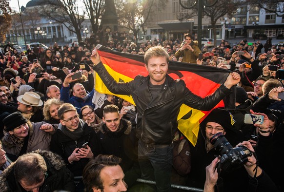 Der neue Formel-1-Weltmeister Nico Rosberg (M) steht am 30.11.2016 in Wiesbaden (Hessen) mit einer Deutschlandfahne in einer Gruppe von Fans. Nico Rosberg wurde in Wiesbaden geboren. Jetzt wurde er hi ...