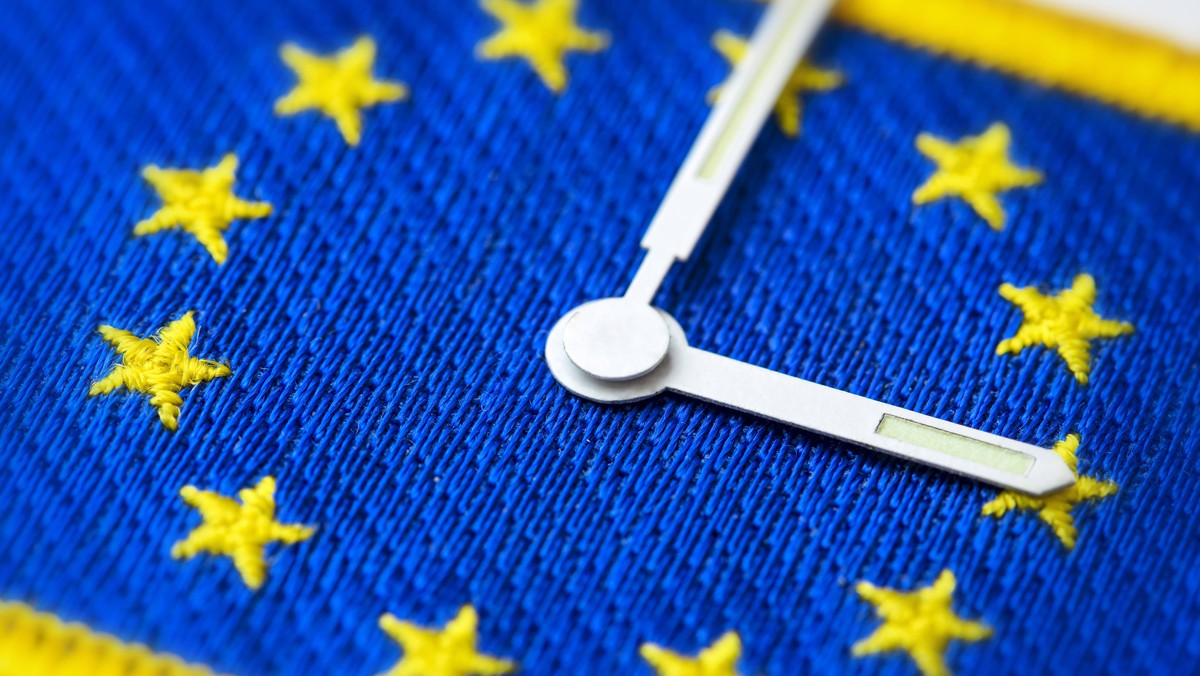 Uhrzeiger auf EU-Fahne, Abschaffung der Zeitumstellung *** Clock hand on EU flag. Abolition of the time change