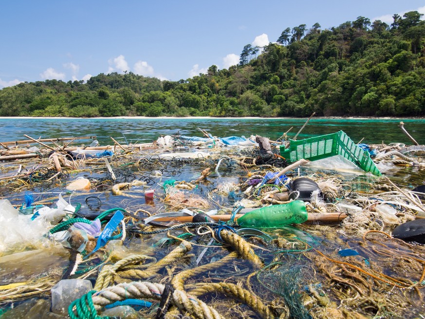 Big patch of ropes and garbage floating on the surface in front of a tropical island