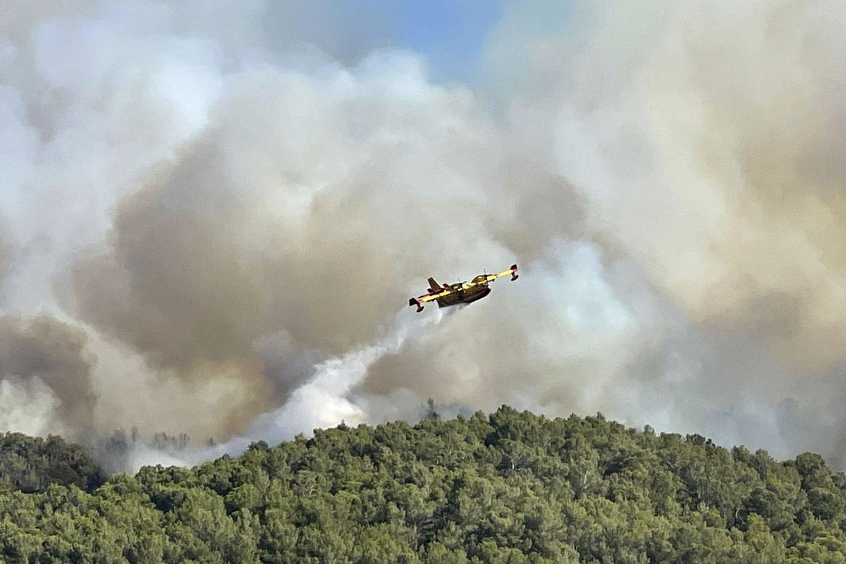 06.08.2025, Frankreich, Corbieres: Dieses von der Securite Civile zur Verfügung gestellte Foto zeigt ein Wasserbombenflugzeug, das Wasser auf den Waldbrand im Corbieres-Massiv in Südfrankreich abwirft ...