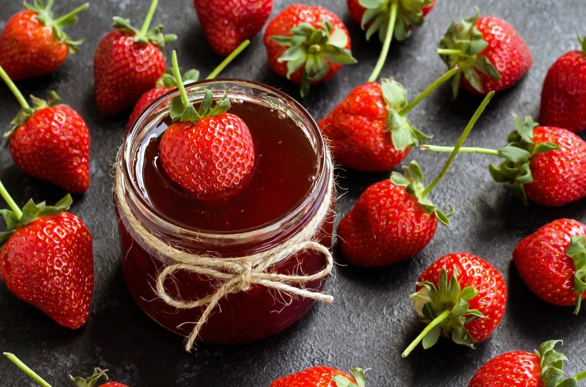Close up taken of Natural strawberry jam with ripe strawberries on black surface