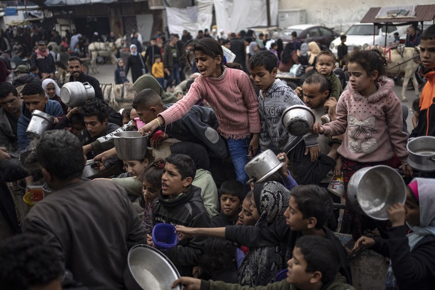 21.12.2023, Palästinensische Gebiete, Rafah: Palästinenser stellen sich für eine kostenlose Mahlzeit an. Angesichts der israelischen Militäroffensive im Gazastreifen wird die humanitäre Lage in dem ab ...