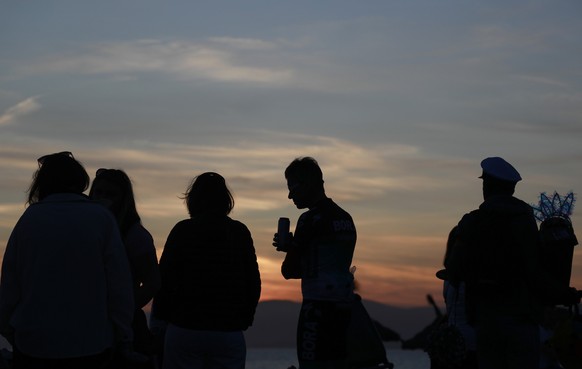 21.04.2023, Spanien, Palma: Menschen halten sich während des Sonnenuntergangs am Strand von Arenal auf. Die Party-Saison auf Mallorca beginnt wieder. Seit Freitag legen die Kultlokale so richtig los.  ...