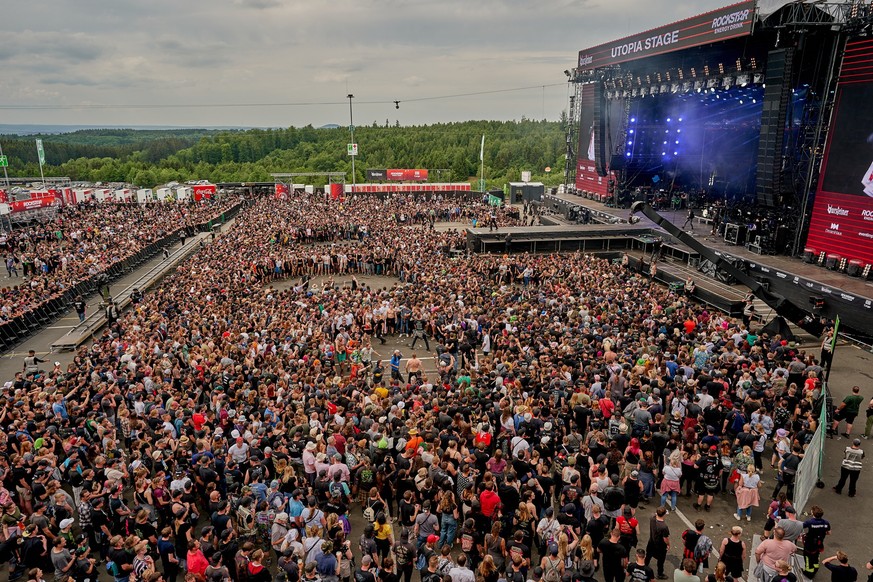 ARCHIV - 03.06.2022, Rheinland-Pfalz, Nürburg: Rockfans tanzen während des Auftritts der der Band &quot;You Me at Six&quot; vor der Hauptbühne des Open-Air-Festivals &quot;Rock am Ring&quot;. Foto: Th ...