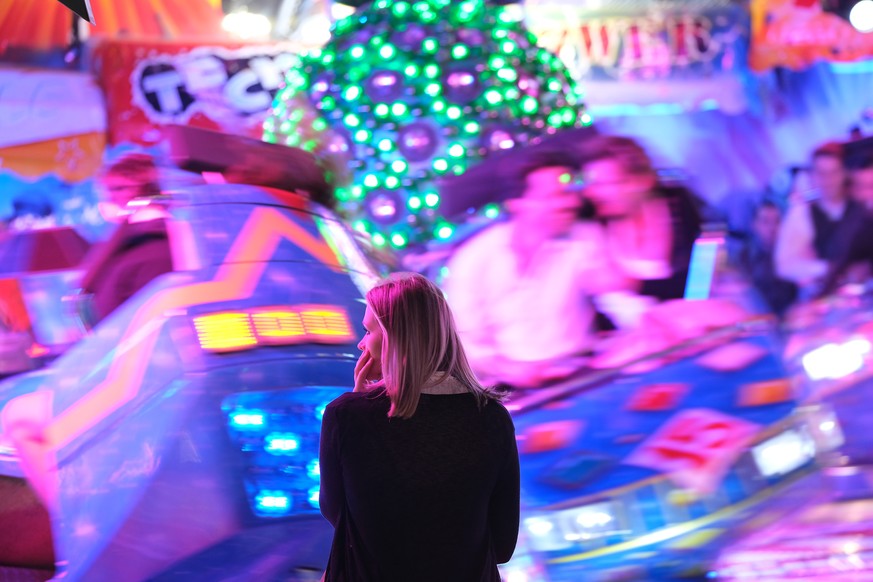 MUNICH, GERMANY - SEPTEMBER 21: A young woman stands next to a high-speed amusement park ride on the first day of the 2019 Oktoberfest on September 21, 2019 in Munich, Germany. This year&#039;s Oktobe ...