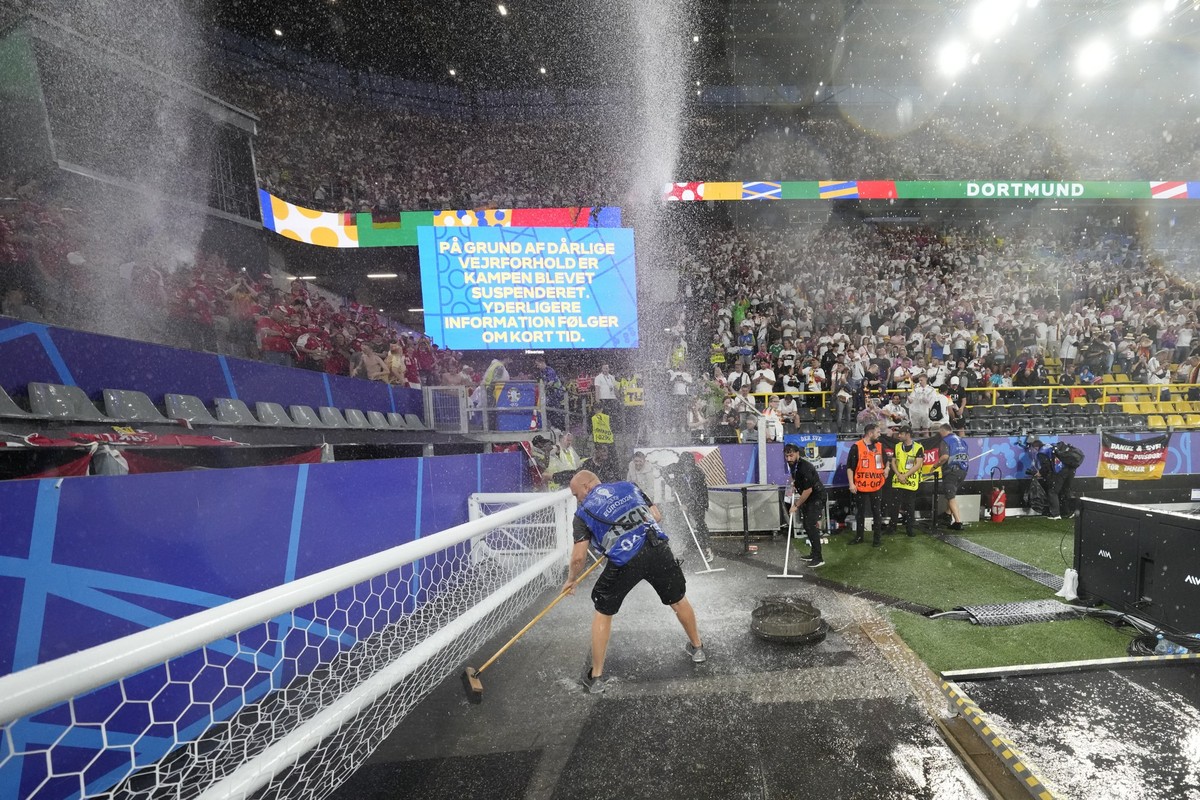 Stadium staff sweep water on the sidelines during a round of sixteen match between Germany and Denmark at the Euro 2024 soccer tournament in Dortmund, Germany, Saturday, June 29, 2024. (AP Photo/Darko ...