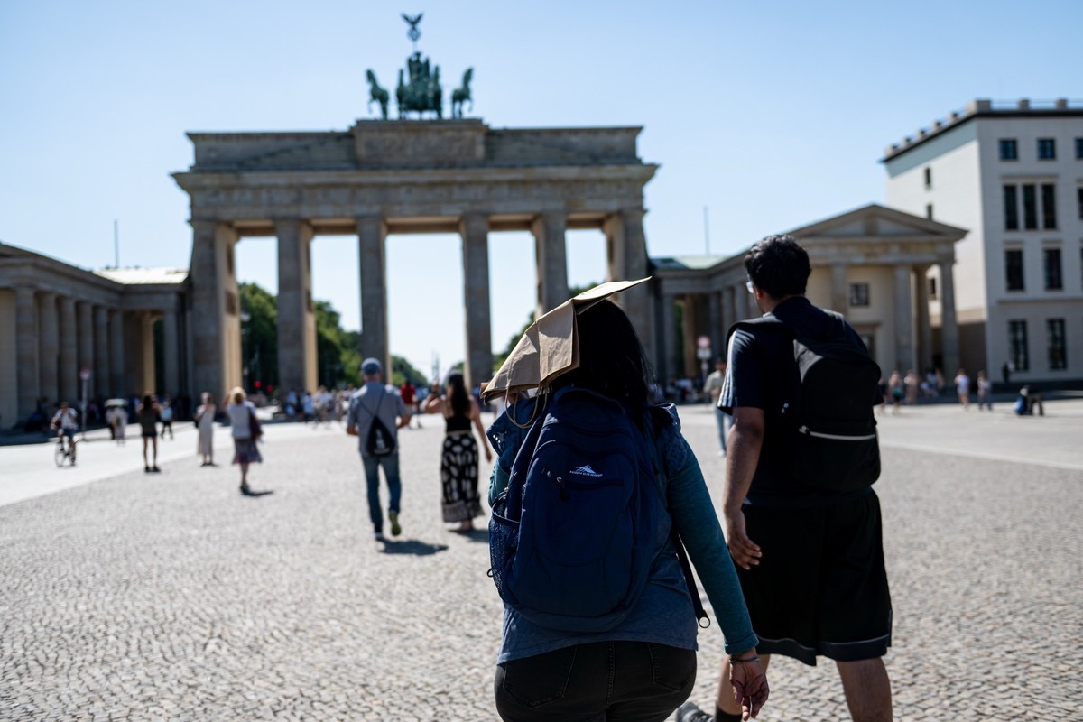 02.07.2025, Berlin: Eine Person hält sich bei hohen Temperaturen auf dem Pariser Platz vor dem Brandenburger Tor eine Papiertüte über den Kopf. Foto: Fabian Sommer/dpa +++ dpa-Bildfunk +++