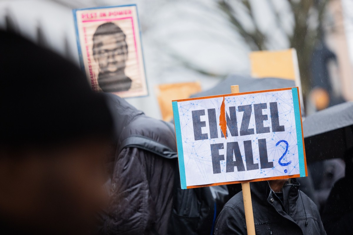 PRODUKTION - 19.12.2023, Nordrhein-Westfalen, Dortmund: Demonstranten stehen mit Plakaten, die das Portrait des 16-j�hrigen Senegalesen Mouhamed Drame zeigen, vor dem Landgericht. Hier beginnt der Pro ...