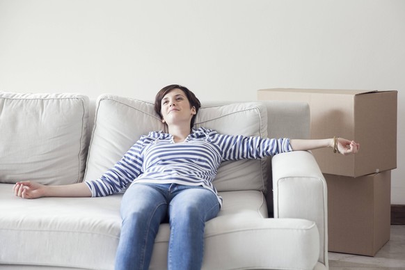 Woman resting on sofa while moving house PUBLICATIONxINxGERxSUIxAUTxONLY Copyright: SigridxOlsson B41570222