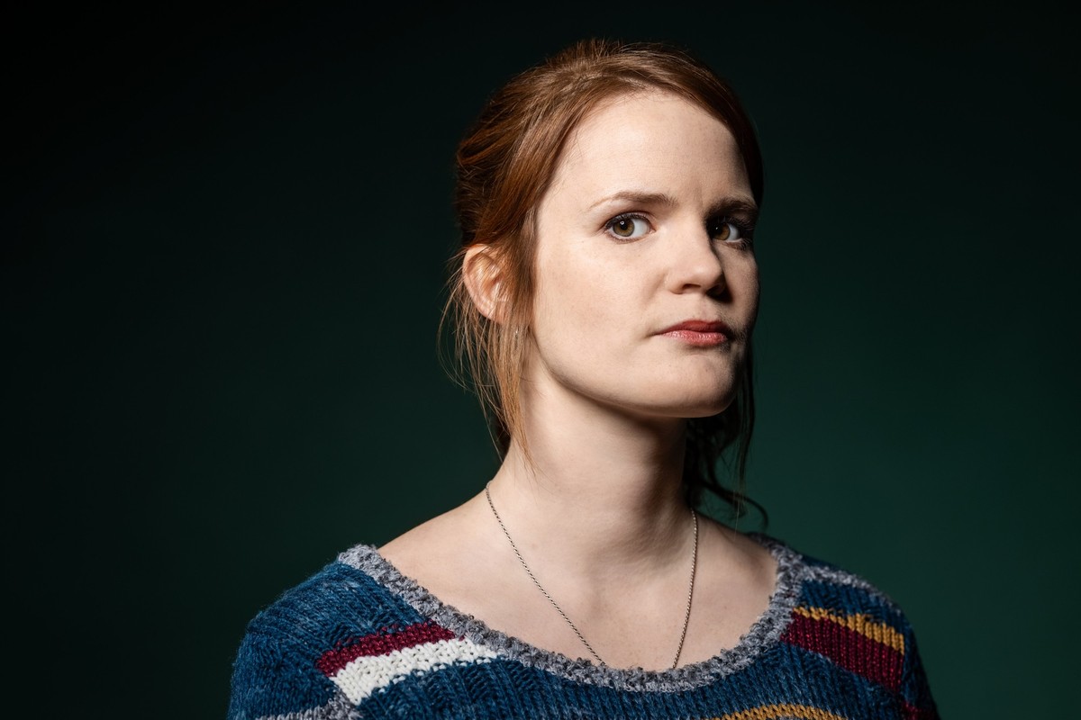Serious looking woman on green background. Mid adult caucasian woman looking suspiciously at camera.