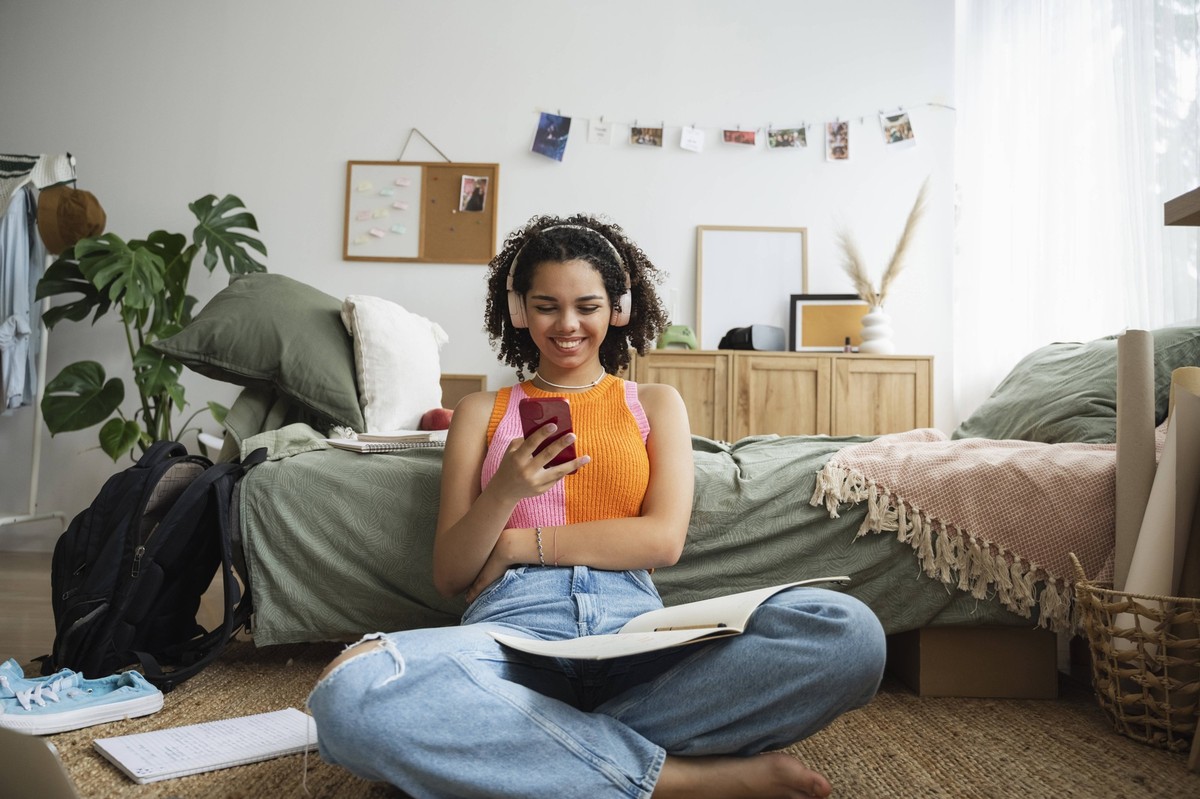 Happy teenage girl using mobile phone in bedroom at home model released, Symbolfoto property released, ALKF00568