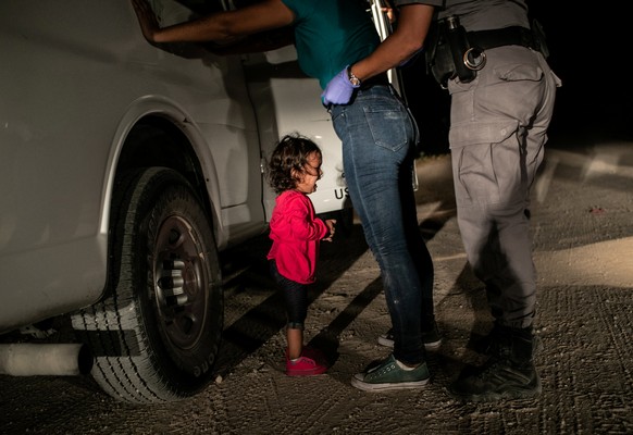 Mitten in Trumps Bestrebungen, die Kinder von illegalen Einwanderern von ihren Müttern und Vätern zu trennen, bricht die kleine Yana aus Honduras in Tränen aus, als ihre Mutter Sandra Sanchez am 12. Juni 2018 in McAllen, Texas, von einem US-Grenzschutzbeamten durchsucht wird.