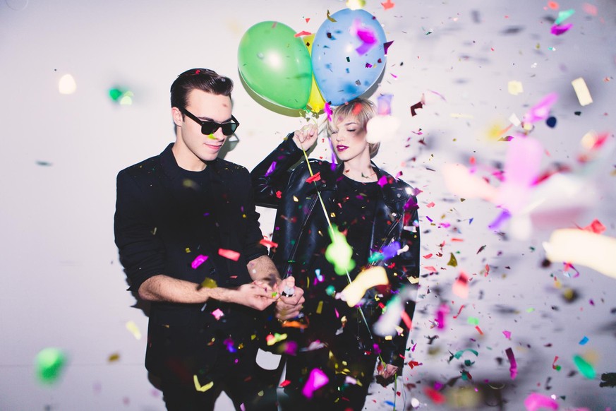 New Year&#039;s / Birthday Party. Girl and boy posing in front of white wall with balloons