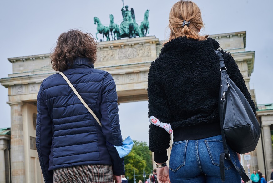 05.10.2020, Berlin: Zwei Frauen gehen mit Mund-Nasenschutz am Oberarm vor dem Brandenburger Tor.. Foto: Annette Riedl/dpa +++ dpa-Bildfunk +++