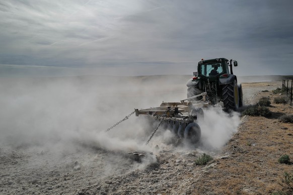 ARCHIV - 09.05.2023, Spanien, Zaragoza: Ein Traktor pflügt das Land auf dem Feld Belchite. Die spanische Regierung greift den von Trockenheit arg geplagten Landwirten des Landes mit einem Milliarden-P ...