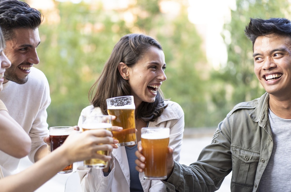 Happy multiracial friends group drinking beer at brewery pub restaurant - Friendship concept with young people having fun and laughing together - Focus on woman at center