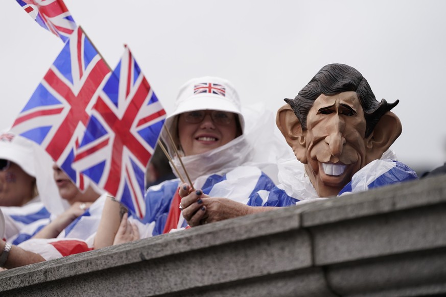 A woman wears a King Charles mask as she waits in Trafalgar Square to see the procession to Westminster Abbey for King Charles III&#039;s coronation in London Saturday, May 6, 2023. (AP Photo/Scott Ga ...