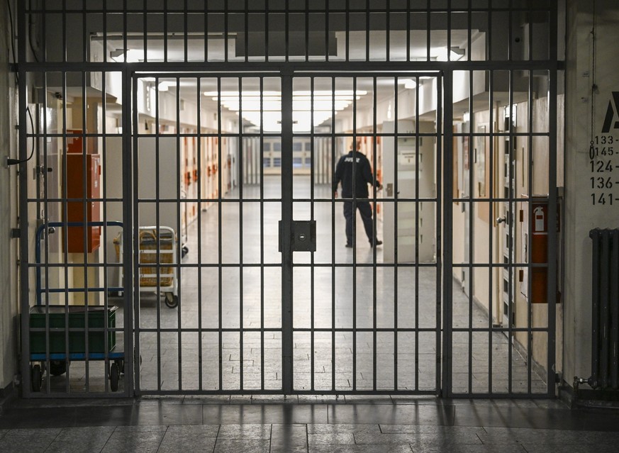 07.12.2023, Berlin: Ein Vollzugsbeamter öffnet in der Justizvollzugsanstalt Moabit bei der Vorstellung der Pläne für einen Suizidpräventionsraum eine Zellentür in einem mit Gittern gesicherten Zelleng ...