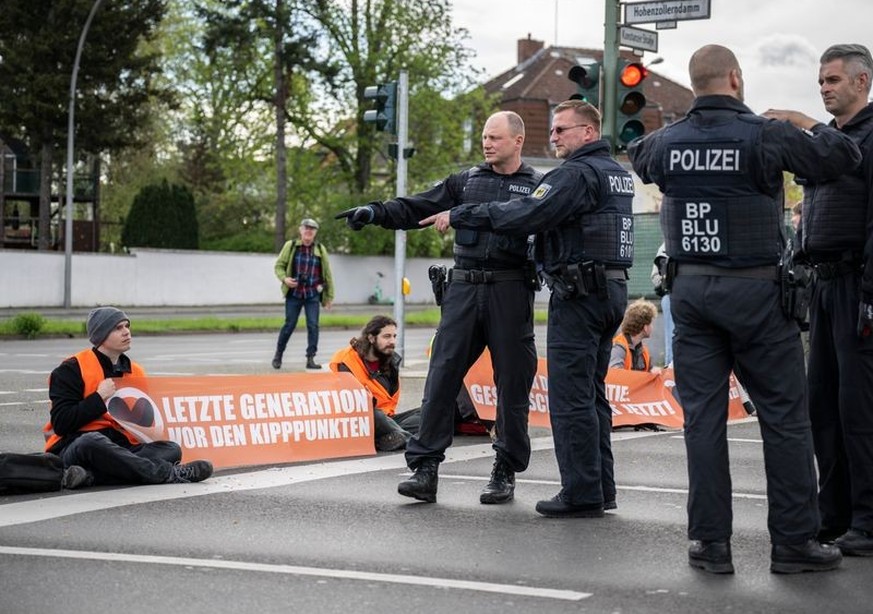 24.04.2023, Berlin: Polizisten besprechen die Vorgehensweise zur Räumung der Kreuzung Hohenzollerndamm/Konstanzer Straße, wo Aktivisten auf der Fahrbahn sitzen. Am Montag will die Letzte Generation na ...