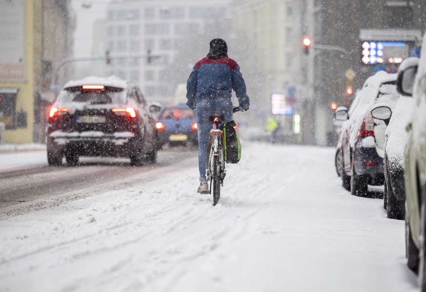 17.01.2024, Nordrhein-Westfalen, Bonn: Ein Radfahrer fährt bei dichtem Schneefall durch die Innenstadt. Schnee und Eis haben Straßen und Gehwege in weiten Teilen Deutschlands in gefährliche Rutschbahn ...