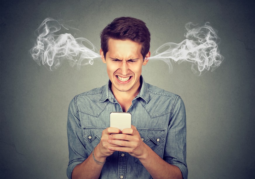 Frustrated angry man reading a text message on his smartphone blowing steam coming out of ears