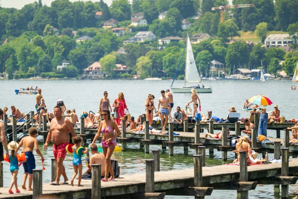 18.06.2023, Bayern, Percha: Sonnenhungrige genießen am Vormittag das warme Wetter auf einem Steg am Starnberger See. Foto: Peter Kneffel/dpa +++ dpa-Bildfunk +++