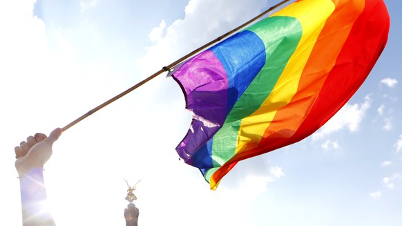 A person holds a rainbow flag in front of the the Berlin Victory Column during the annual Gay Pride parade, also called Christopher Street Day parade (CSD), in Berlin, Germany July 28, 2018. REUTERS/A ...