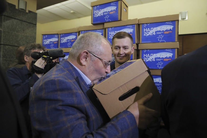 31.01.2024, Russland, Moskau: Boris Nadeschdin, ein liberaler russischer Politiker, der bei den Präsidentschaftswahlen am 17. März kandidieren will, küsst eine der Schachteln mit Unterschriftenbögen,  ...