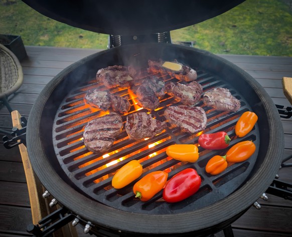 A kamado egg type barbeque grill standing on a living house terrace with beef sirloin steak, filet mignon and vegetables to be cooked on open fire Model Released Property Released xkwx outdoor coal po ...