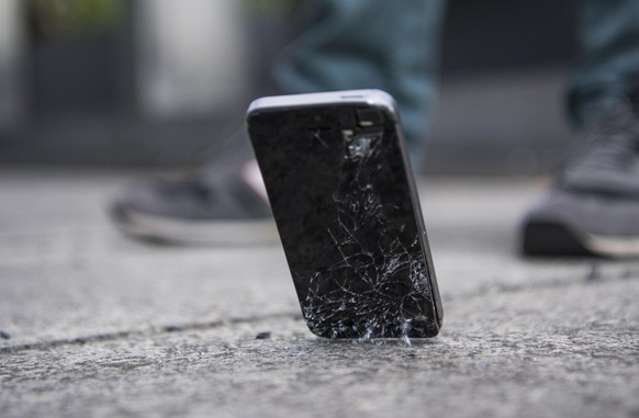 28.05.2018, Berlin: Ein Mann laesst ein Smartphone auf den Boden fallen.