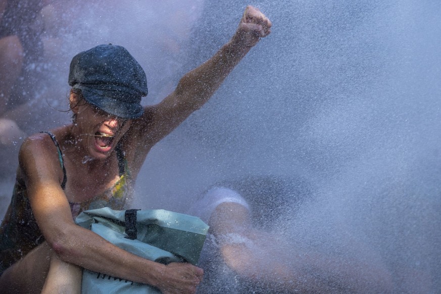 09.09.2023, Niederlande, Den Haag: Eine Aktivistin gestikuliert bei einem Klimaprotest, organisiert von der Umweltschutzbewegung Extinction Rebellion, während die Polizei Wasserwerfer gegen die Demons ...