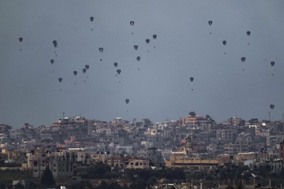 Parachutes drop supplies into the northern Gaza Strip, as seen from southern Israel, Friday, March 8, 2024. (AP Photo/Leo Correa)