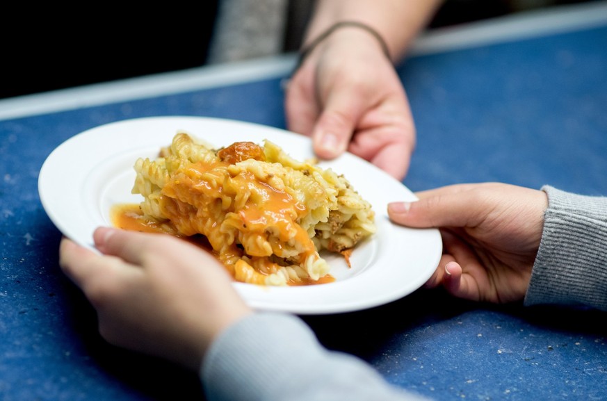ARCHIV - 18.10.2018, Niedersachsen, Hannover: Eine Mitarbeiterin verteilt in der Mensa einer Grundschule das Mittagsgericht, einen Nudelauflauf mit So