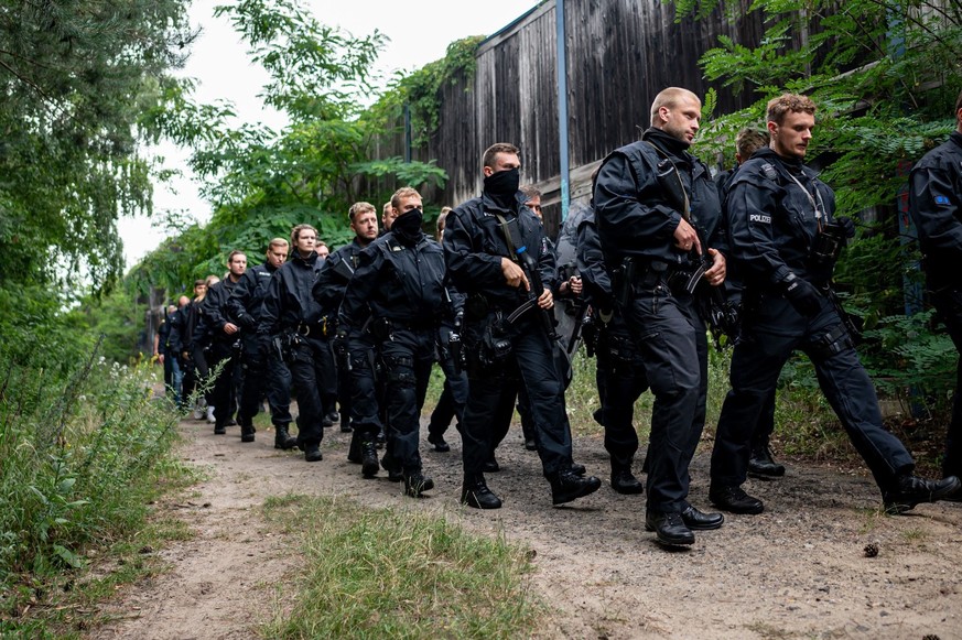 21.07.2023, Brandenburg, Kleinmachnow: Polizisten laufen im Bereich der südlichen Landesgrenze von Berlin. Ein gefährliches Wildtier soll in der Nacht zum Donnerstag in Brandenburg entlaufen sein und  ...