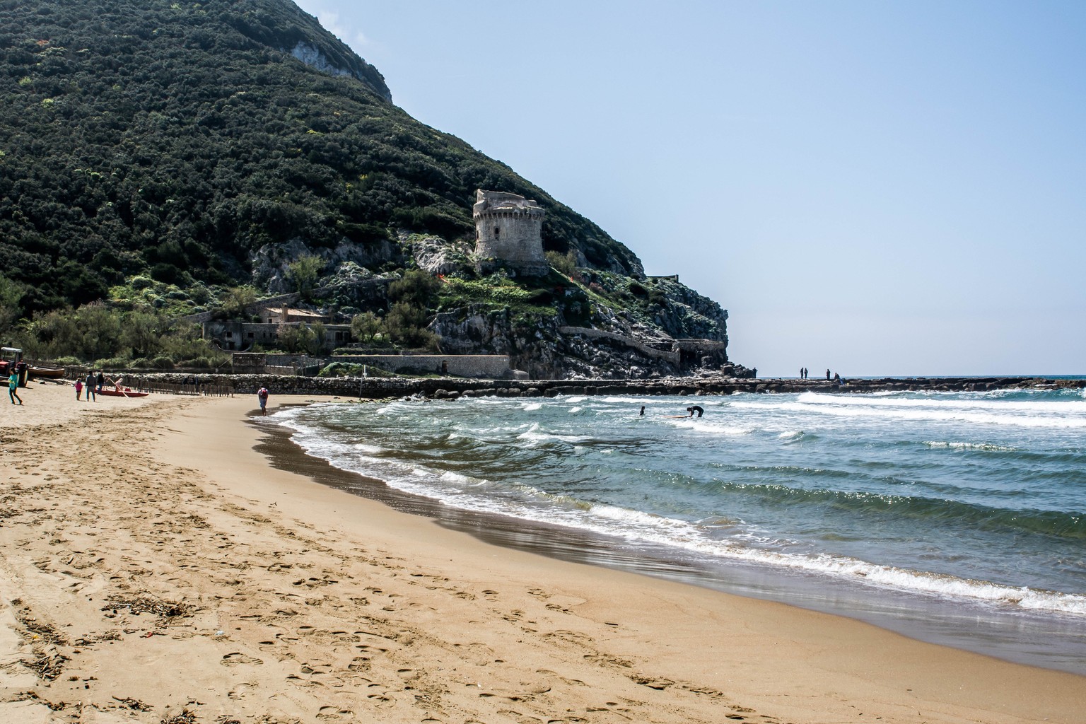 Sabaudia, Italy - April 18, 2015: the beach of Sabaudia with early wet and tourists stroll. In the background Torre Paola erected in 1563 to counter the constant pirate raids.