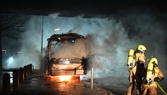 01.01.2023, Berlin: Feuerwehrmänner löschen an der Sonnenallee einen Reisebus, der von Unbekannten angezündet worden war. Foto: Paul Zinken/dpa +++ dpa-Bildfunk +++