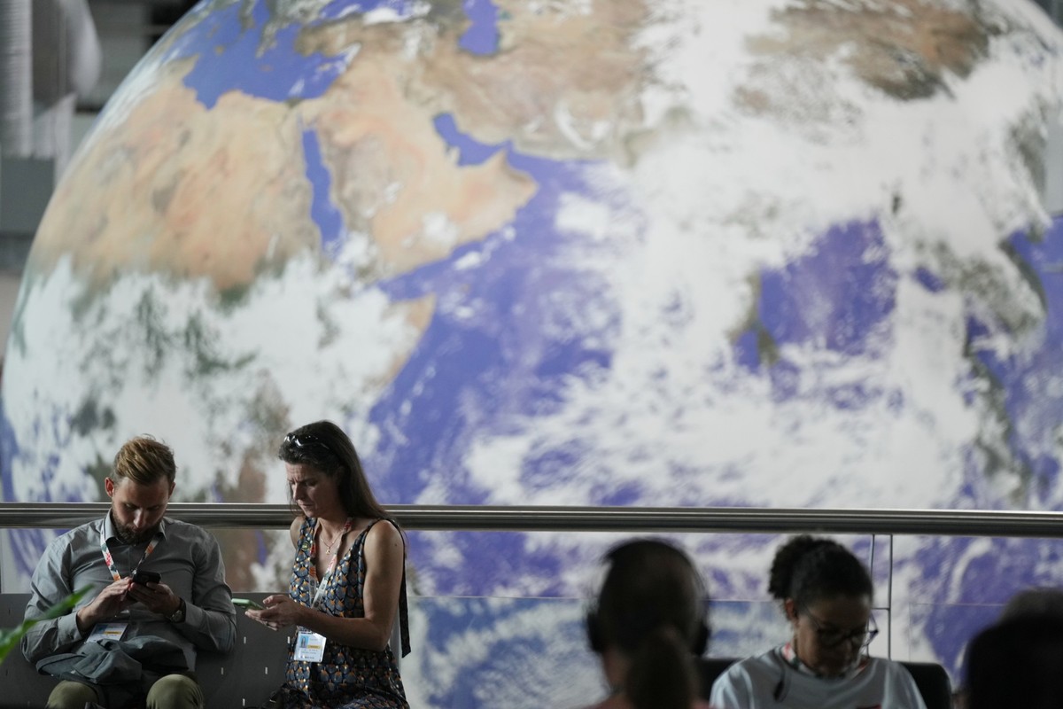 Attendees sit with a backdrop of a globe in a lobby at the side events pavilions of the COP30 U.N. Climate Summit, Tuesday, Nov. 11, 2025, in Belem, Brazil. (AP Photo/Fernando Llano)