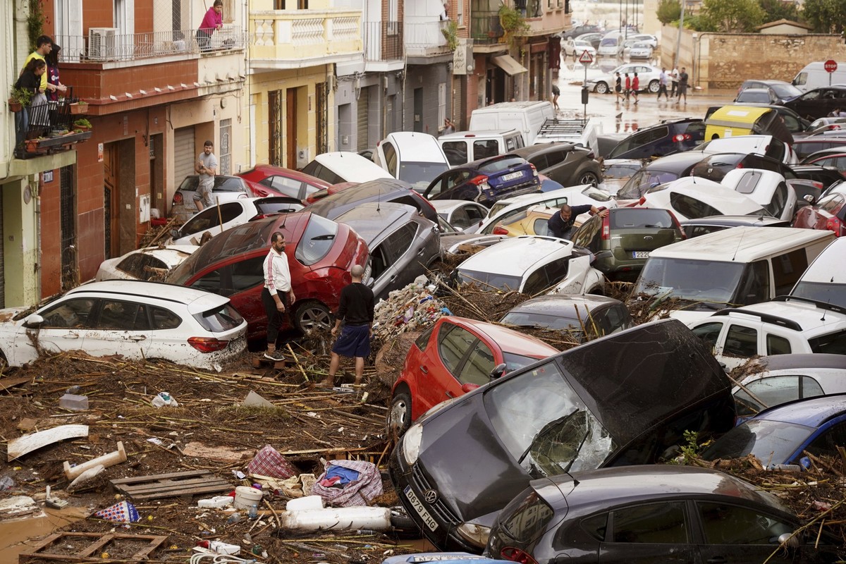 dpatopbilder - 30.10.2024, Spanien, Valencia: Anwohner betrachten durch die Wassermassen aufgestapelte Autos. Foto: Alberto Saiz/AP +++ dpa-Bildfunk +++