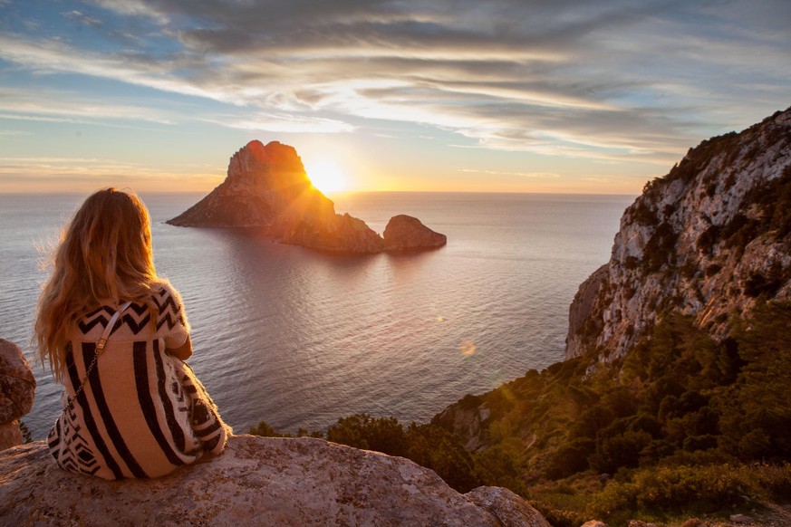 Woman back to the front watching a beautiful sunset at the beach. The beach is called Es Vedra, in Ibiza and belongs to balearic islands, in Spain