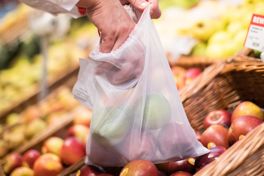 ARCHIV - 26.10.2017, Nordrhein-Westfalen, Kaarst: Ein Mann legt in einem Supermarkt einen Apfel in ein Mehrweg-Frischenetz.