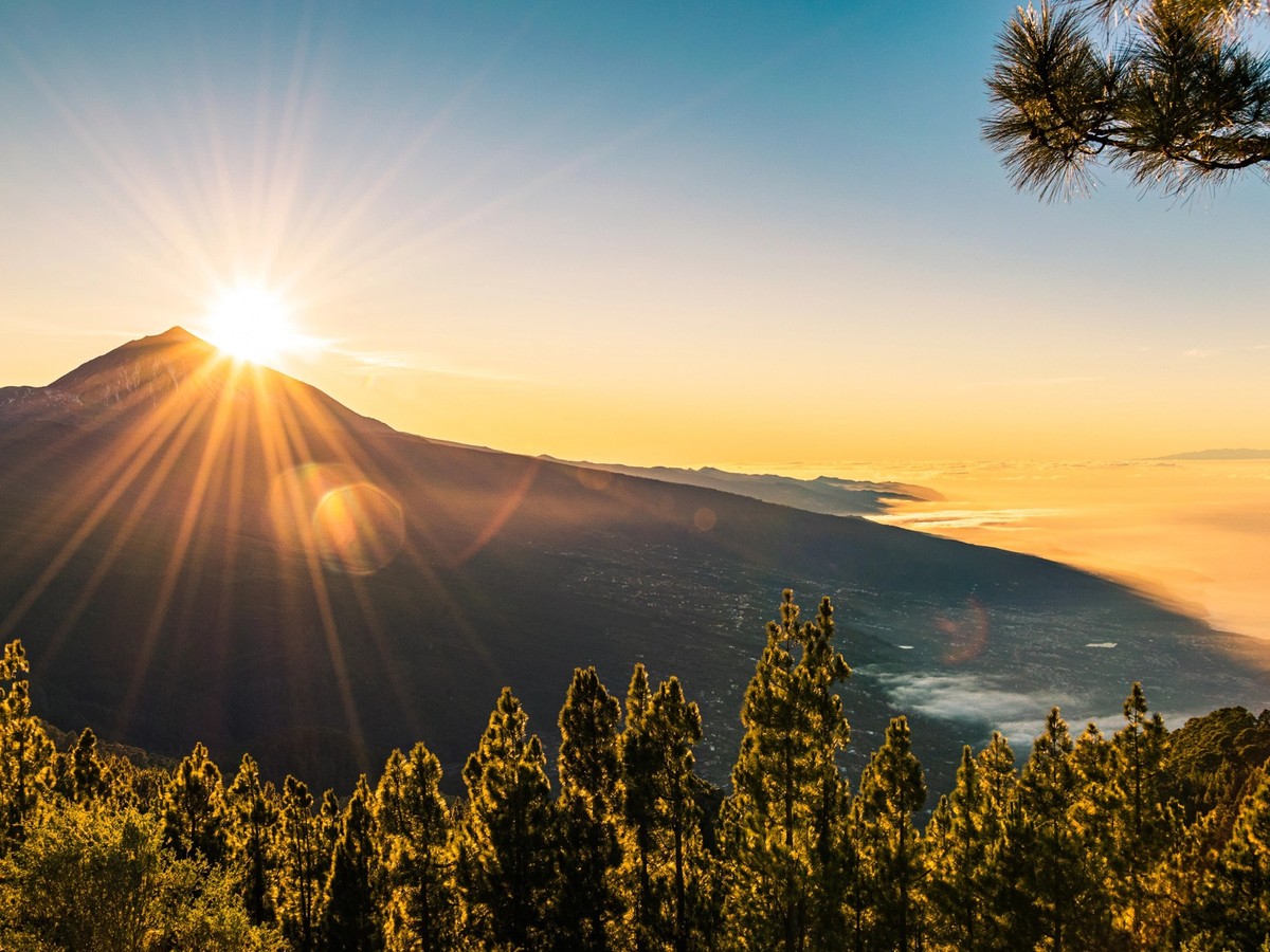 Sun flare as the sun sets behind Mount Teide, seen from Mirador de Chipeque viewpoint. Tenerife, canary Islands, Spain.