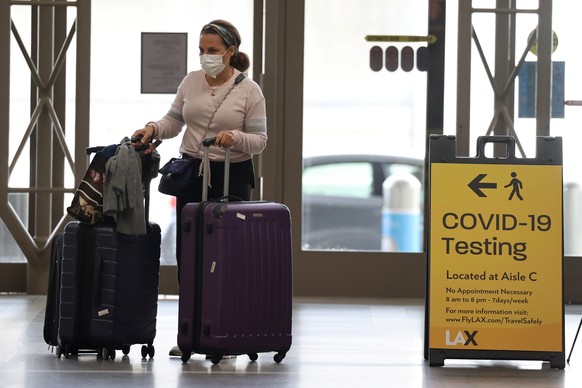 A woman walks past a coronavirus testing sign at Tom Bradley international terminal at LAX airport, as the global outbreak of the coronavirus disease (COVID-19) continues, in Los Angeles, California,  ...