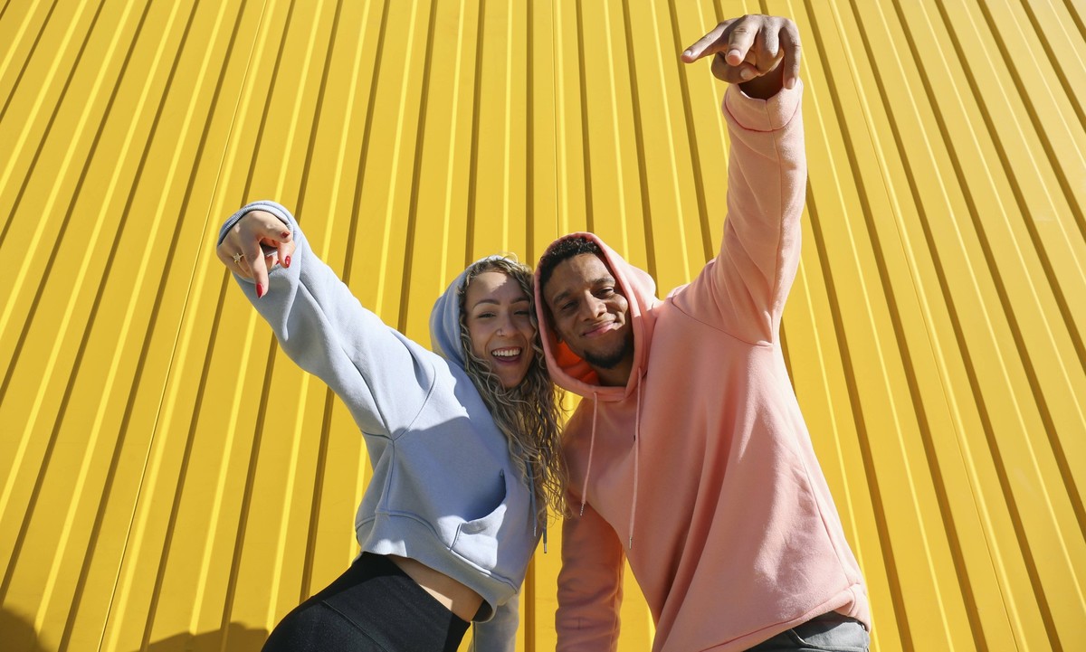 UNNUSED Happy couple gesturing peace sign in front of yellow wall model released, Symbolfoto, SYEF00528