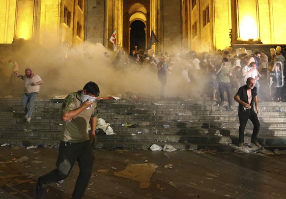 Opposition demonstrators run away as police fire a volley of tear gas at Georgian Parliament during a protest in Tbilisi, Georgia, Friday, June 21, 2019. Police have fired a volley of tear gas at a ma ...