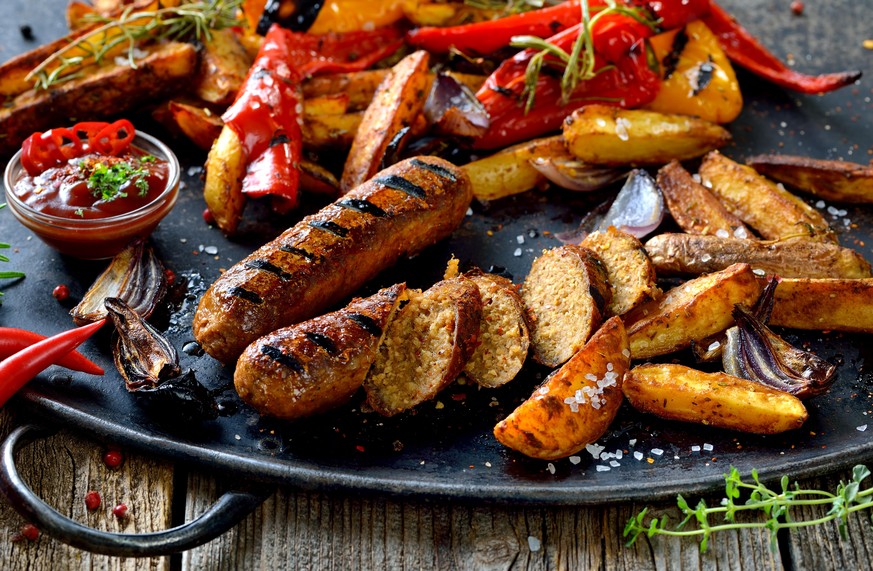 Grilled vegan sausages with hot sauce, potato wedges and vegetables