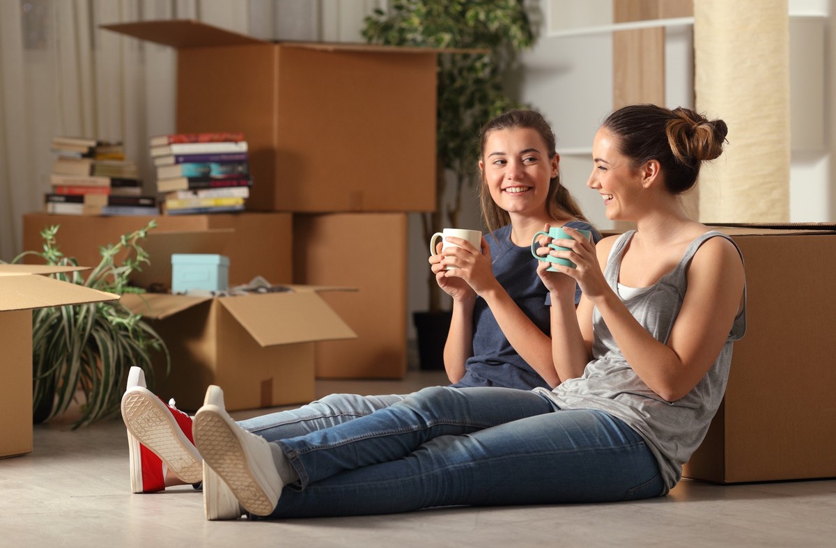 Happy roommates moving home resting and talking