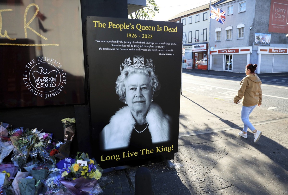 FILE - A woman walks past a picture of Queen Elizabeth II on the Loyalist Shankill Road in west Belfast, Sept. 10, 2022. Britain&#039;s longest-reigning monarch and a rock of stability across much of  ...