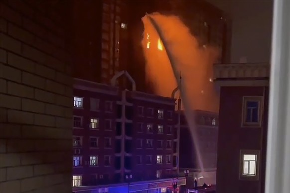 FILE - In this image taken from video, firefighters spray water on a fire at a residential building that killed several people in Urumqi in western China&#039;s Xinjiang Uyghur Autonomous Region, on N ...